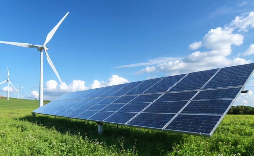 Wind turbine and solar panels in a picturesque off-grid location, illustrating a wind-solar hybrid renewable energy system.