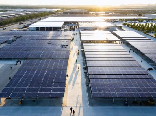 Aerial view of a cutting-edge solar manufacturing facility in the U.S., highlighting bustling production zones and solar panels gleaming under the sun.