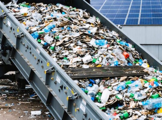 "Advanced recycling machinery processing colorful plastic waste for solar panel recycling in a warehouse setting."