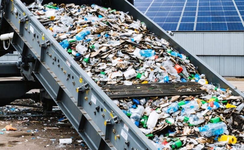 "Advanced recycling machinery processing colorful plastic waste for solar panel recycling in a warehouse setting."