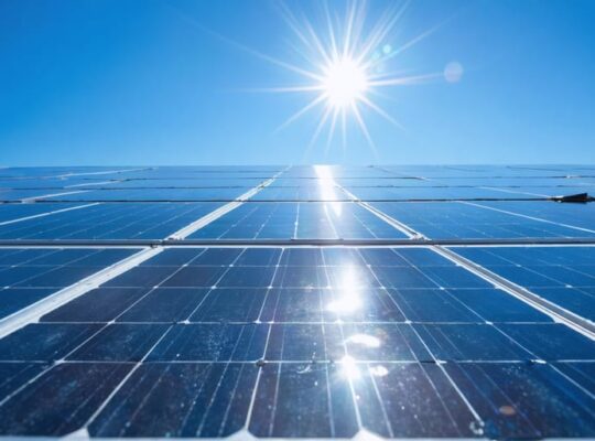 "Close-up of a modern solar thermal installation with shining solar panels and collectors, under a clear blue sky."
