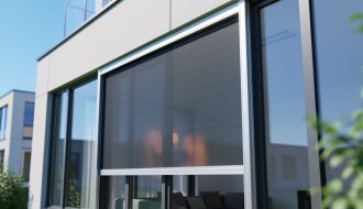 Exterior-mounted custom solar window screen installed over a large building window in bright daylight, with the mesh pattern and mounting rails visible.