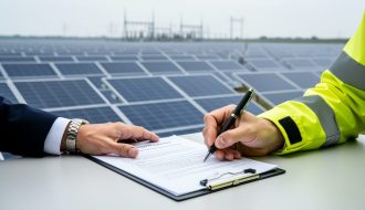 Two people signing a solar public-private partnership contract next to a utility-scale solar farm with rows of photovoltaic panels in the background.